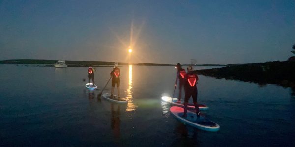 Group Paddleboarding Illuminated Under Full Moon